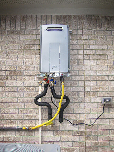 A tankless water heater installed on the side of a house.