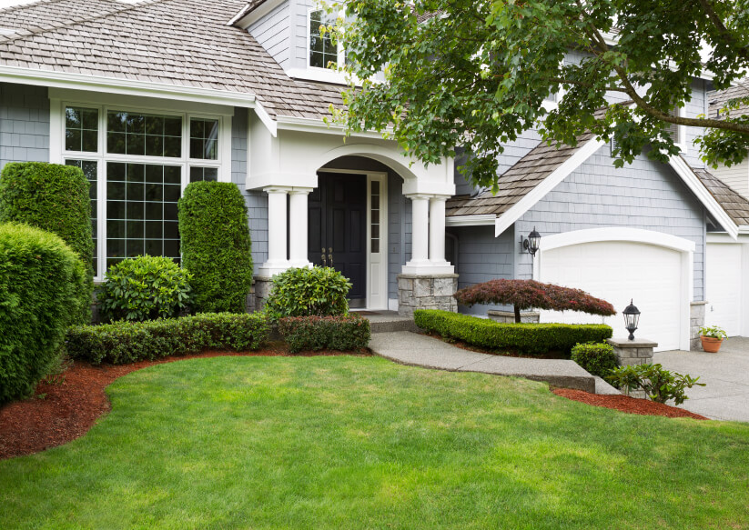 the from of a home with light gray siding with bright landscaping