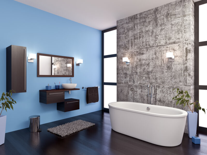Master bathtub in an open bathroom with blue walls, tile surround, and wood floor