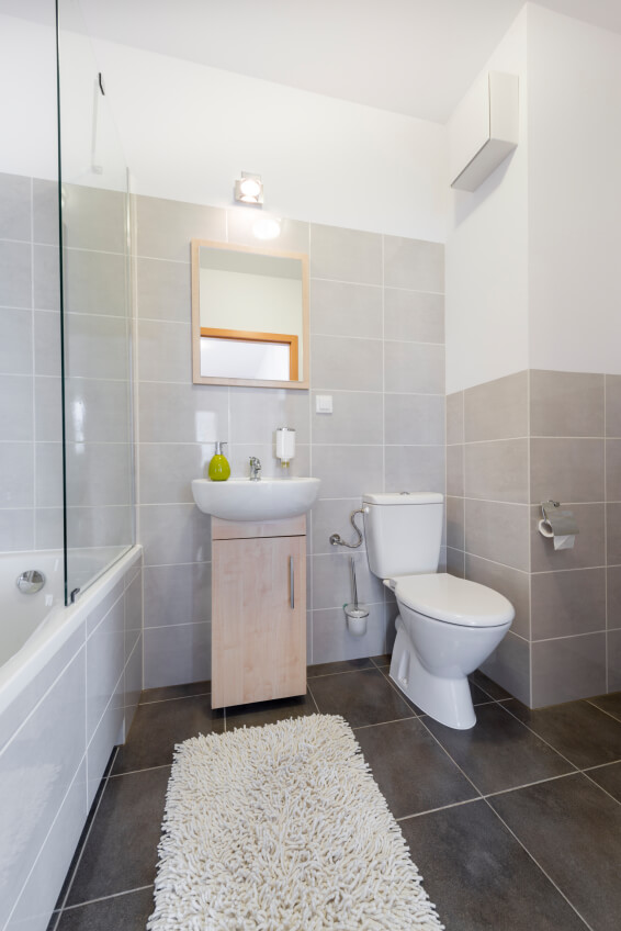 Small bathroom with a low profile vanity and a tub with a glass door and shower