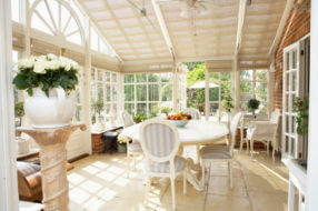 Four-season room with dining furniture and retractable shades on the ceiling