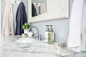 Image of a sink in a bathroom with white marble countertops and chrome hardware