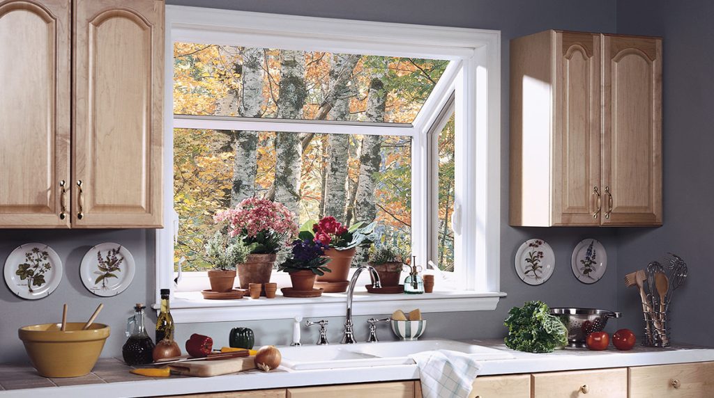 White garden window filled with plants over a kitchen sink