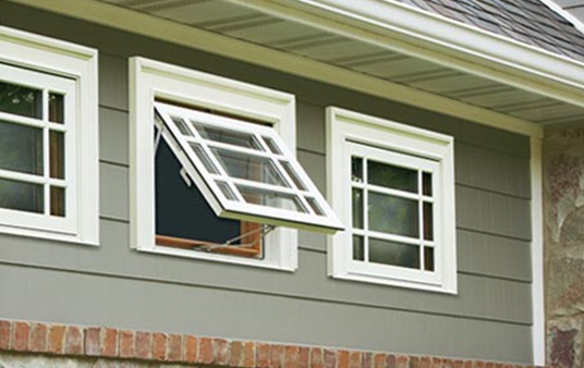 Three white awning windows with muntins on a home's exterior with the middle window open