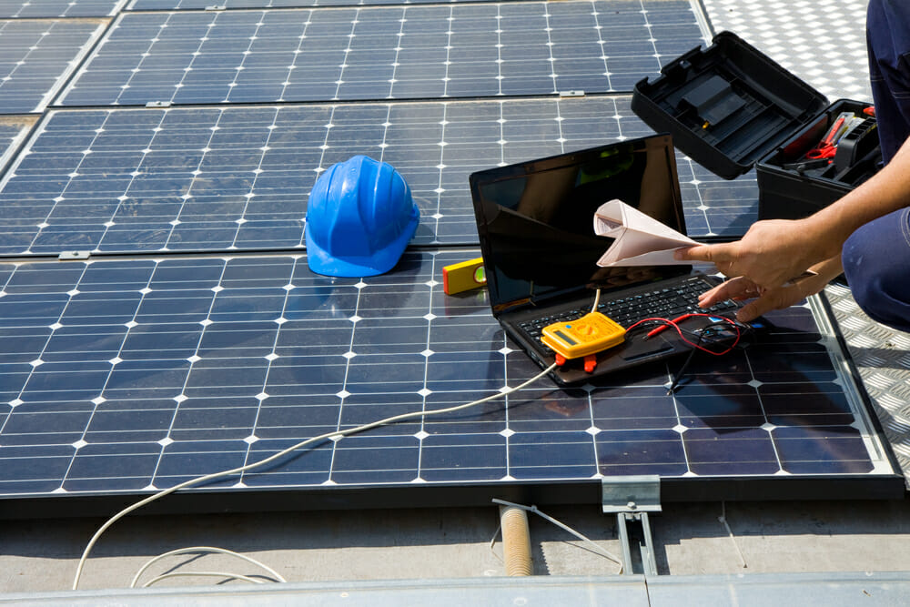 A contractor installs a solar panel onto a roof. 