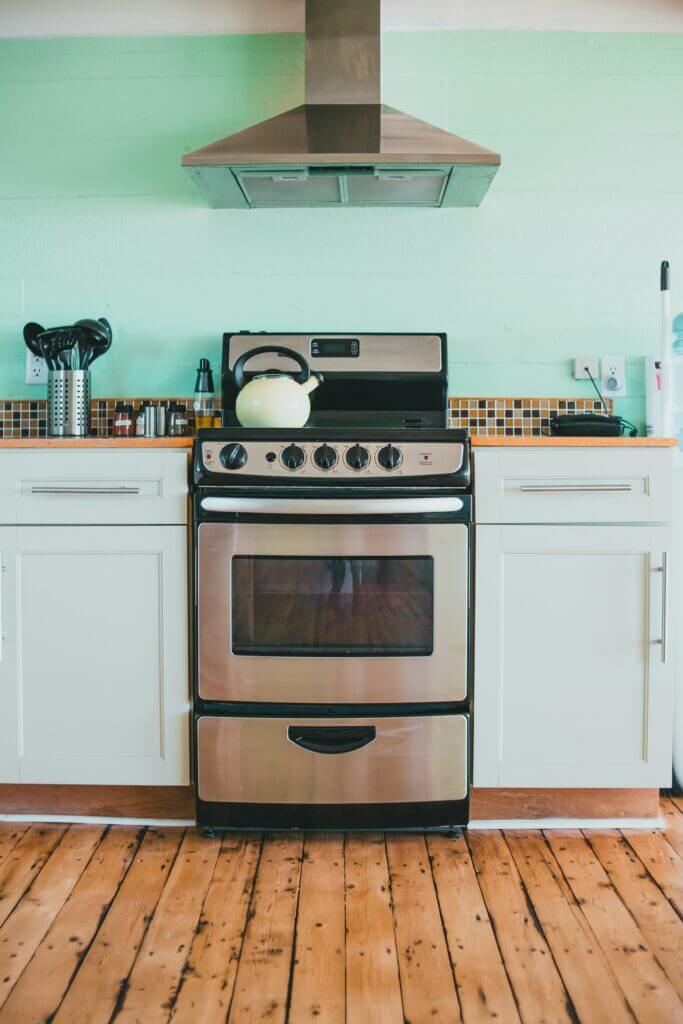 A standalone oven in a bright kitchen with a stove stop and a range hood