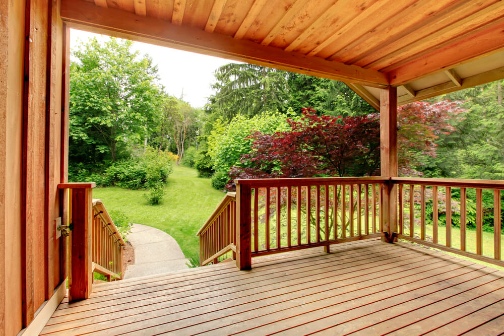 Wooden deck with railing leading to a large, open yard.