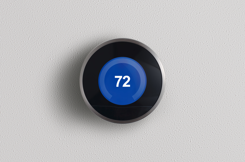 A simplistic photo of a round, modern, programmable digital thermostat, on a clean white wall in cooling mode.