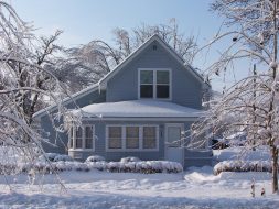 Photo of a light blue home covered in snow