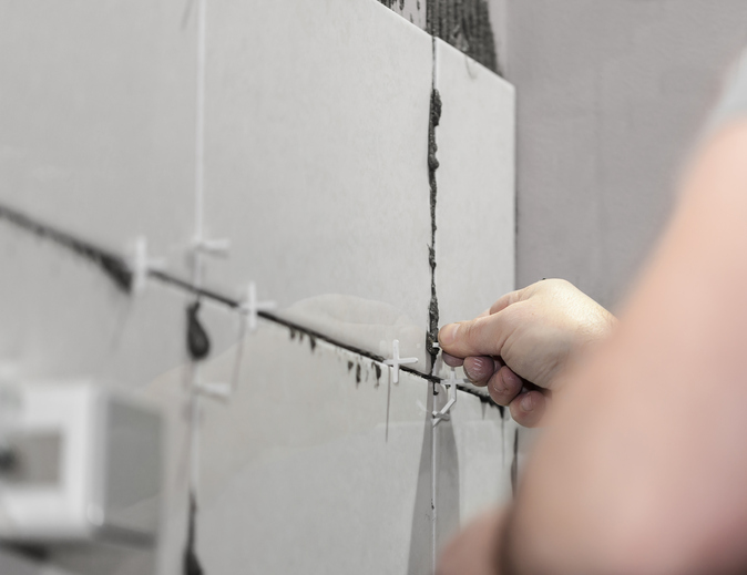 Worker tiler puts ceramic tiles on a wall