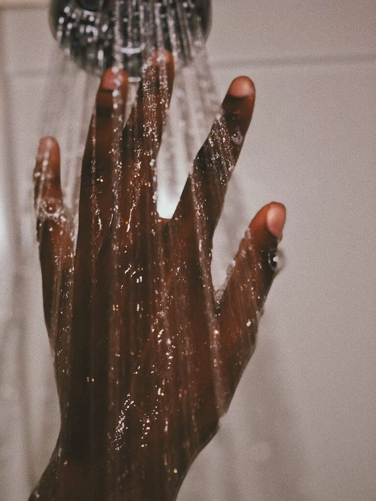 A hand reaching into the hot water from a shower