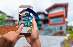 Image of a phone in the foreground and a home in the background showing smart home apps that are protecting the home