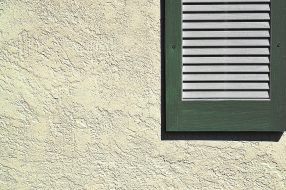 Green shutter on exterior stucco wall