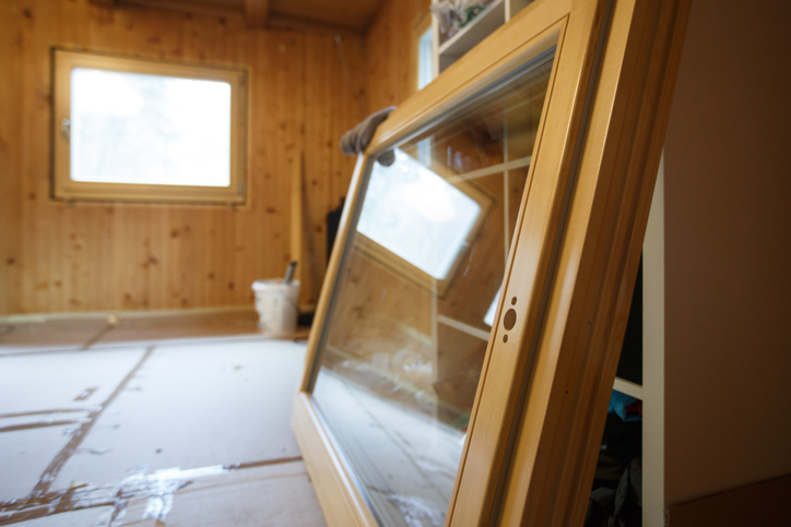 New efficient, three pane wooden window prepared for installation in an old wooden house, changing wasteful old windows. Home renovation, sustainable living, energy efficiency concept.