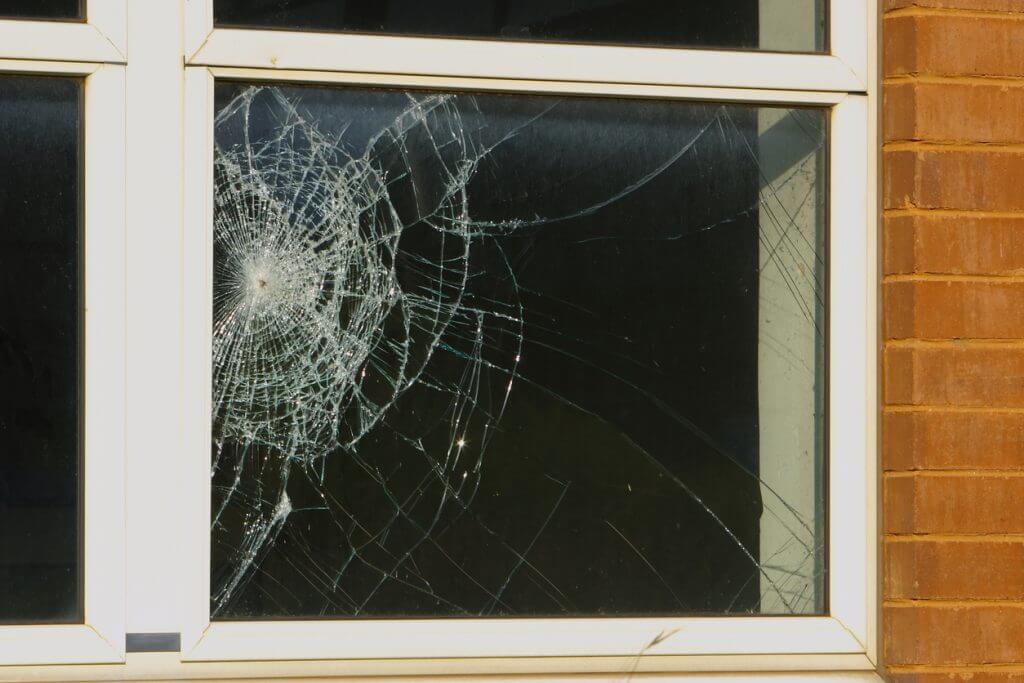 Image shows a window with broken glass in the corner as if hit by something and shattered