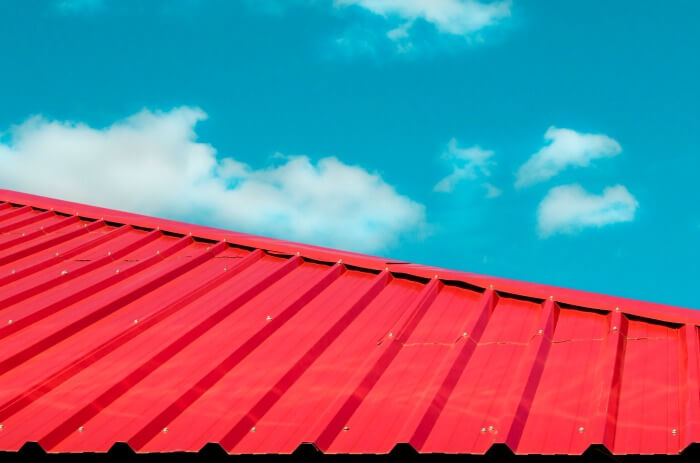 Red tile roof with blue sky and cloud background