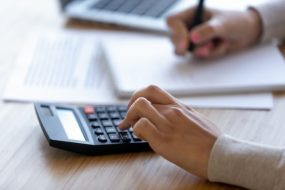 Image of hands using a calculator and taking notes