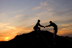 Roofers installing roof at sunset