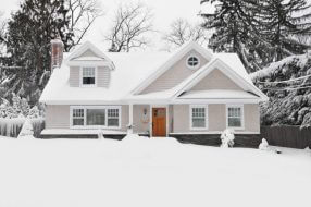 a light gray home during a snowfall