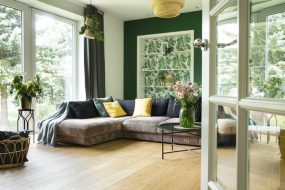 Modern and cozy living room with corduroy sofa, pillows, big window to the garden. Bright and sunny space.