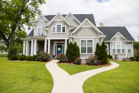 a gray home with a sidewalk on the front lawn