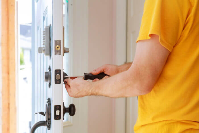 Man using screwdriver to install a new lock for a home security system