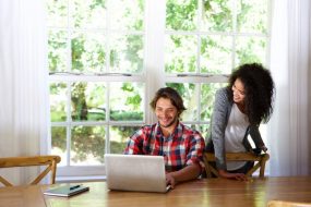 Portrait of a happy young couple sitting at table with laptop