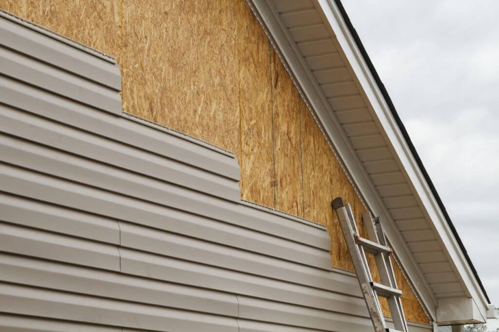 a close up shot of a home getting grey siding installed