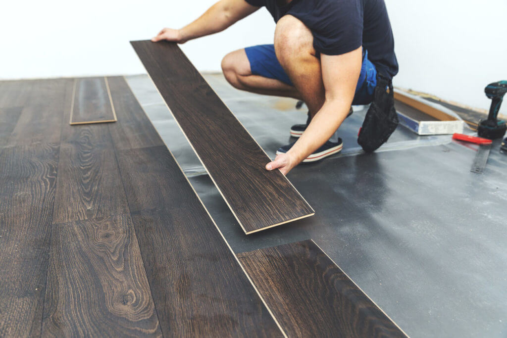 Image of a contractor installing dark wood-look flooring