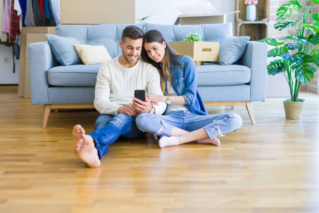 Homeowners looking at a phone on the floor of their living room