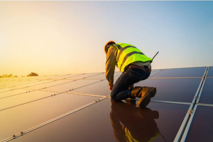 Portrait of engineer man or worker, people, with solar panels or solar cells on the roof in farm. Power plant with green field, renewable energy source in Thailand. Eco technology for electric power.