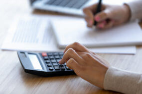 Female professional using calculator for business financial accounting, accountant or bookkeeper making calculations managing money, woman calculating bills expenses taxes making notes, close up view