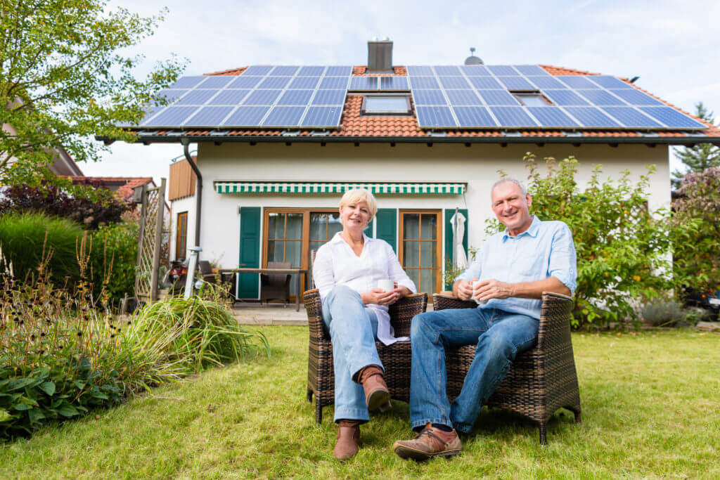 Couple of man and woman sitting in front of their home or house in wicker chairs