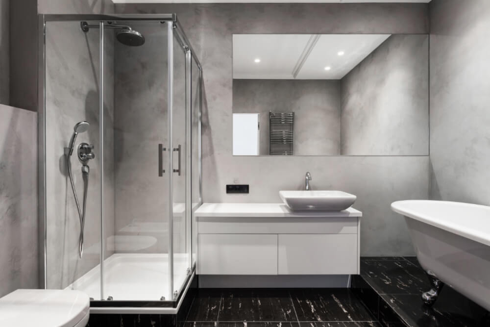 A modern bathroom with black tile floors and a framed shower