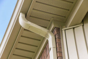 Aluminum gutter and downspout near the roof of a house.
