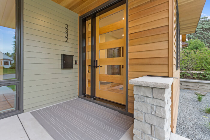 Photo of a home's front door from the exterior showing wood siding