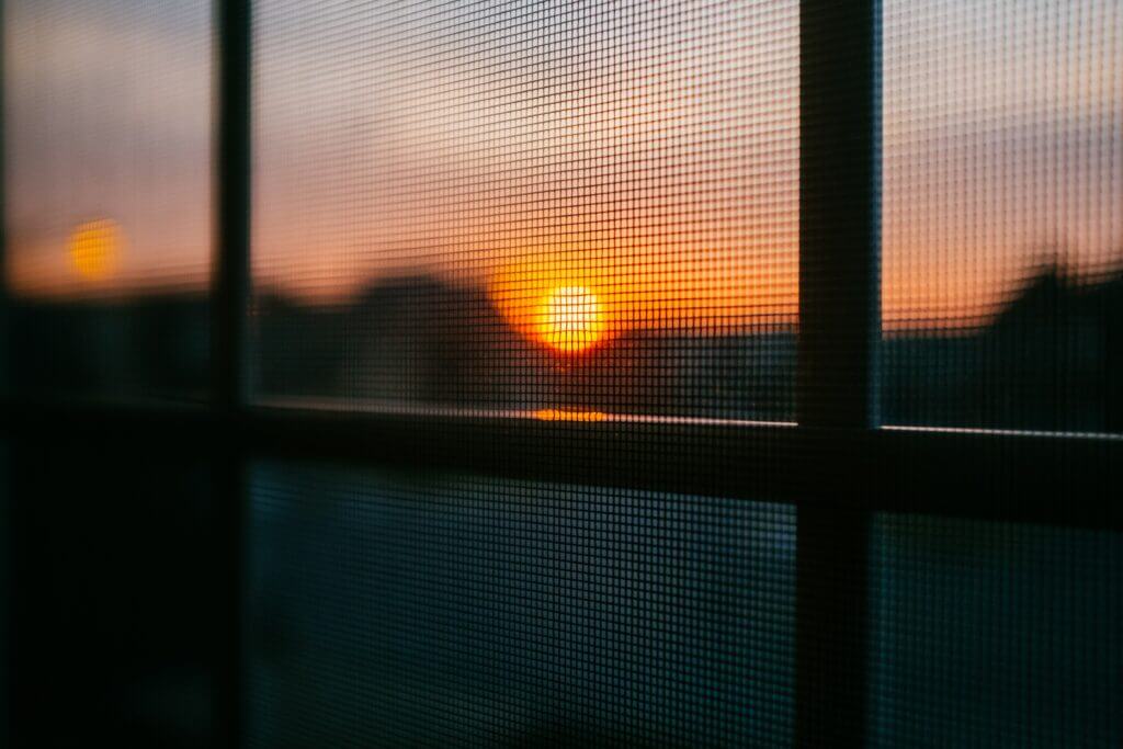 Distorted sunset view through a window screen