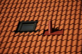 Close-up image of a roof with terracotta colored tile shingles