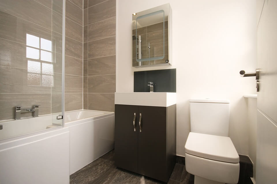 Large tiles creating a feature wall around a tub in a small bathroom