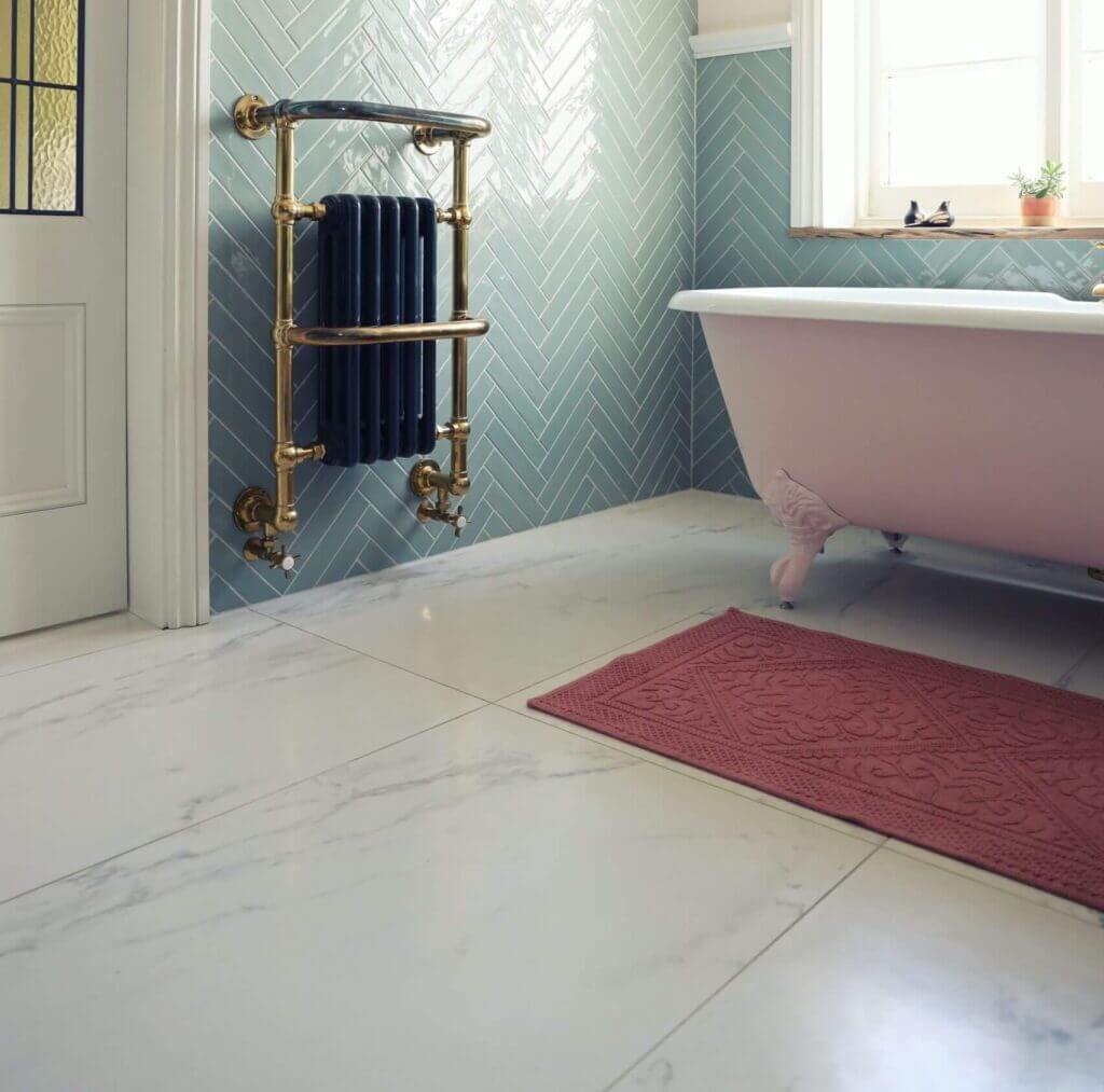 Large bathroom with clawfoot tub, herringbone tile on the walls, and stained glass door