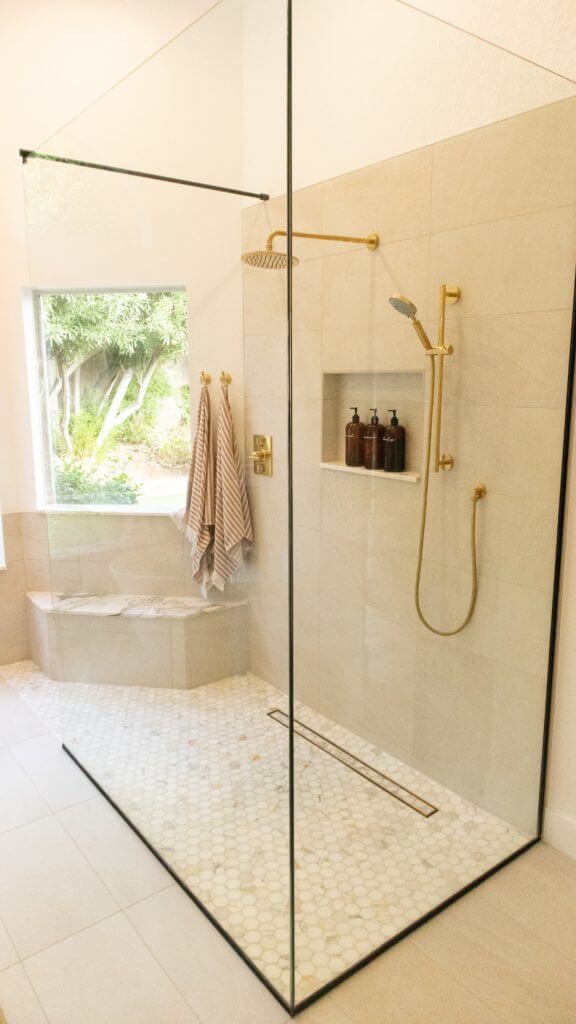 Luxury walk in shower with champagne colored tile and gold fixtures