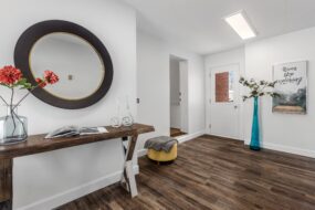 Photo of a living room and entryway with white walls and dark wood-look laminate floors