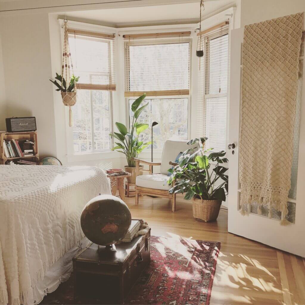 bay window in bedroom with plants and a chair