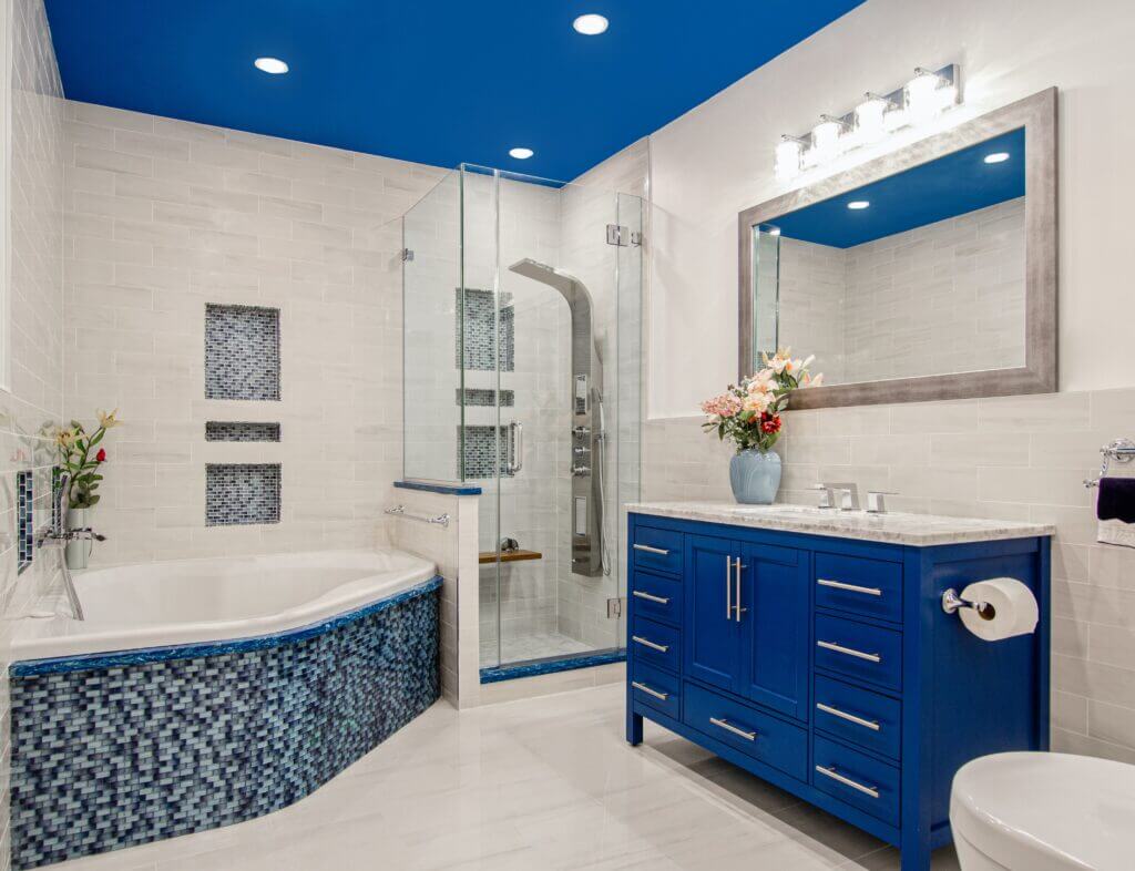 Image shows a blue and white bathroom with recessed lighting