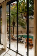 Image shows the inside to outside view of windows gazing into a pool and decking