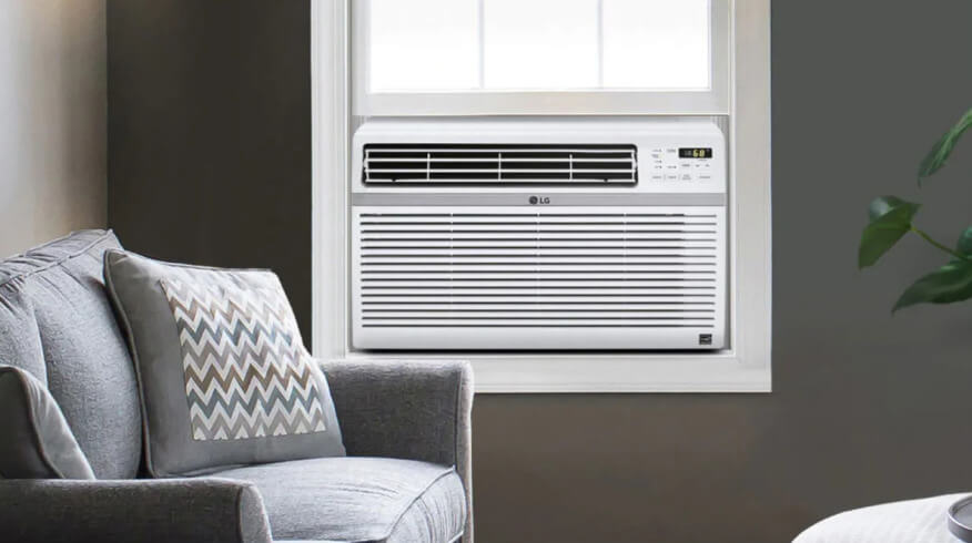 Image shows an LG window AC unit in a cozy room with a gray chair