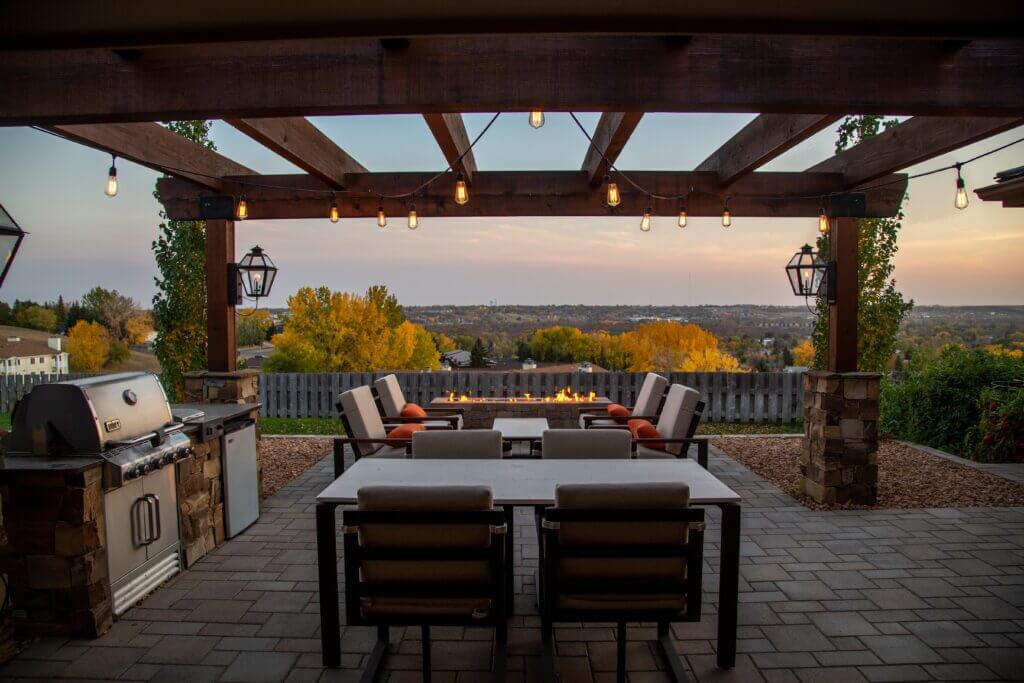 Image shows an outdoor patio with a built-in kitchen and a pergola
