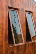 Exterior view of open awning windows on a home with cafe lights reflected in the glass