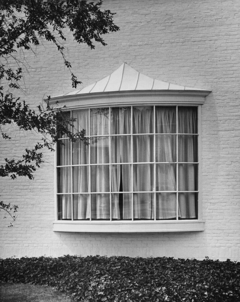 black and white photo of an exterior of a home with a bow window