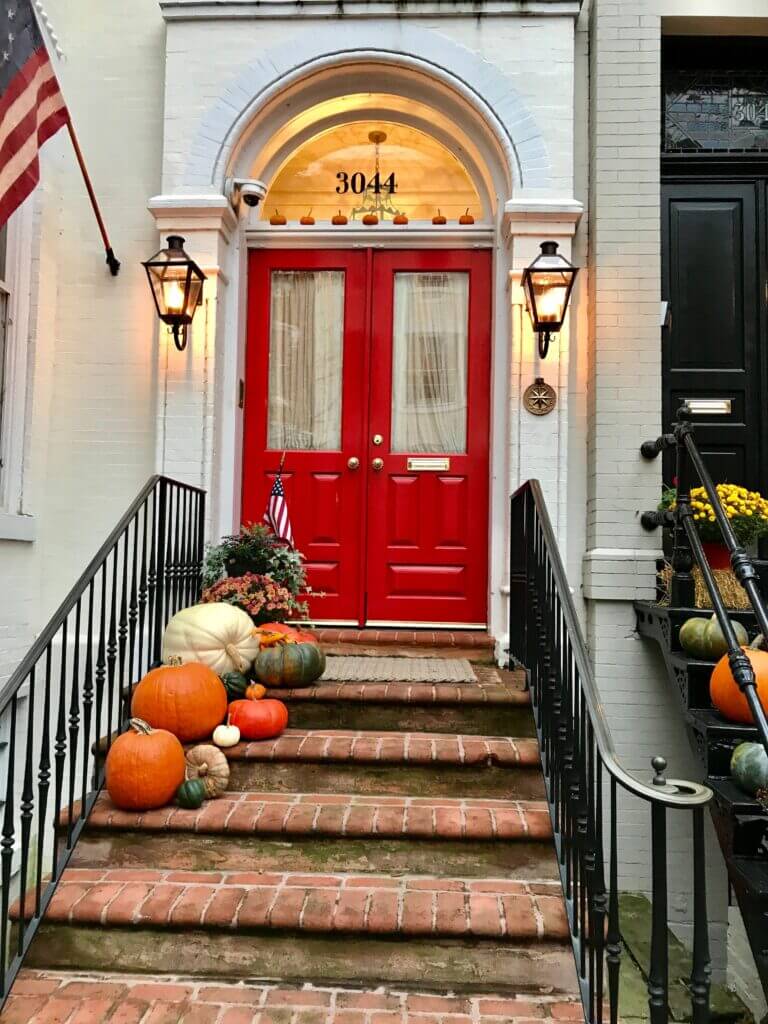 Front porch with a red door, pumpkins, and lanterns